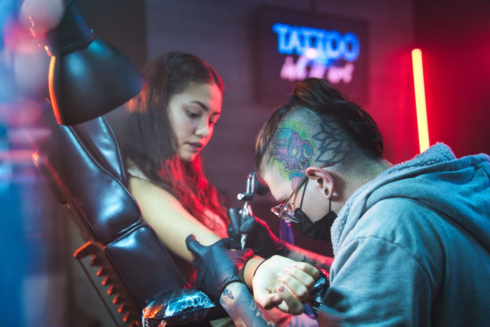 Tattoo artist drawing a design on a client in the parlour