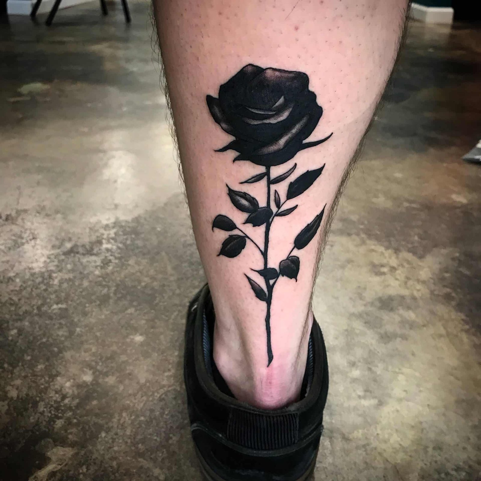 Black rose tattoo on a leg